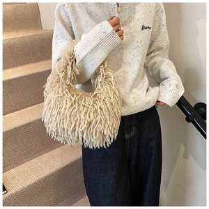 Gros plan d'un sac à main en peluche ivoire avec texture duveteuse et chaîne élégante
