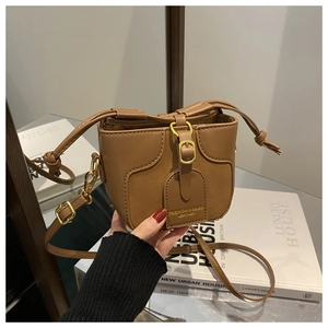 Detail of a brown leather bucket bag for girls with adjustable strap and metal buckle