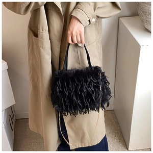Detail of black faux feather crossbody bag with gold chain strap and plush texture