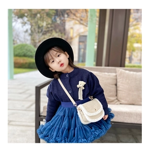 Close-up of navy blue knitted cardigan with bear brooch and beige plush crossbody bag
