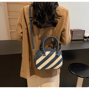 Dettaglio della borsa a tracolla a righe blu e crema in un elegante contesto lifestyle