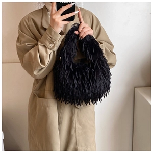 Gros plan du sac à main noir en peluche texturé porté sur un trench-coat classique