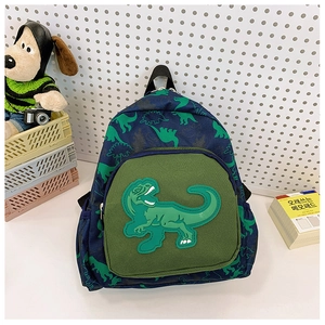 Dettaglio di uno zaino blu per bambini con stampe di dinosauri verdi su sfondo bianco