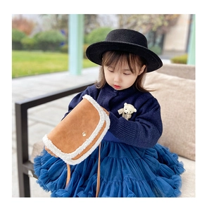 Detail of child crossbody bag with brown suede texture and white faux fur trim and gold buckle