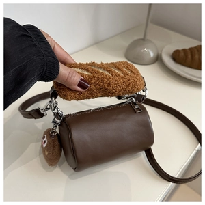 Detail of cylindrical kids bag showing furry baguette handle and cute plush charm