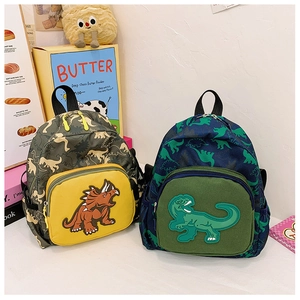 Dettaglio di due zaini per bambini con motivi a dinosauro e stampe mimetiche colorate