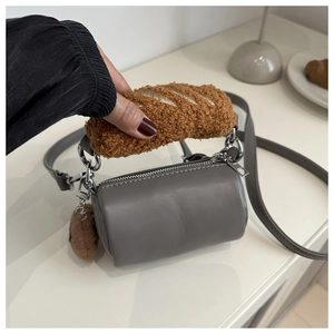 Detail of grey cylinder bag with brown plush handle and matching crossbody strap