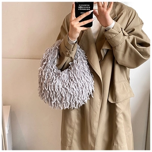 Gros plan d'un sac demi-lune en fausse fourrure grise avec un trench-coat kaki