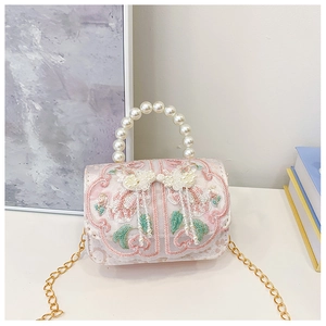 Close-up of pink lace shoulder bag with floral embroidery and pearl handle details