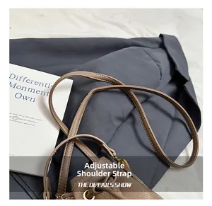 Détail du sac seau en cuir marron avec bandoulière réglable et crochet doré