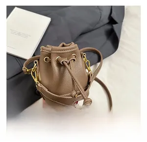 Détail d'un mini sac seau en cuir marron avec cordon de serrage et finitions en métal doré