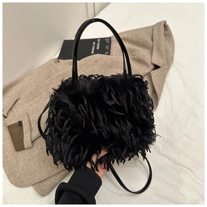 Detail shot of black plush crossbody bag with leather strap on beige wool coat