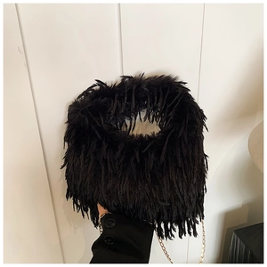 Détails de la texture en fausse fourrure noire et de la chaîne dorée du sac à bandoulière