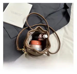 Détail du sac seau marron à cordon montrant l'intérieur spacieux et les bretelles en cuir
