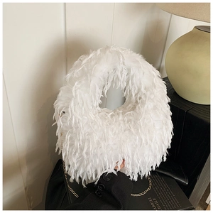 Détail d'un sac seau en plumes blanches avec chaîne dorée dans un cadre élégant