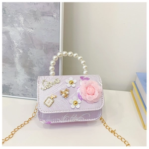 Detail of purple crossbody bag featuring pearl handle, 3D floral accents and chain strap