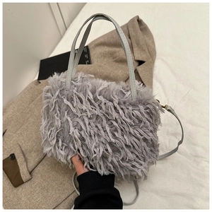 Close-up of light gray plush handbag with fringe tassels and soft faux fur texture