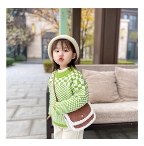 Detail of child green checkered sweater and brown frosted bag with white fuzzy trim
