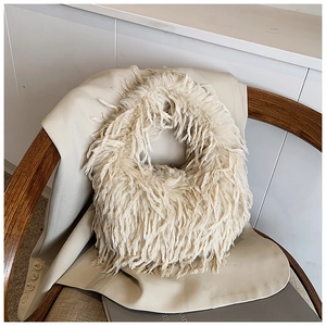 Détail d'un sac en fausse fourrure crème posé sur un blazer élégant et une chaise en bois