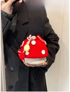 Close-up of handmade crochet mushroom drawstring bag with red polka dot cap and yellow charm