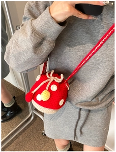 Mirror selfie showing the scale and long red strap of the crochet mushroom bucket bag