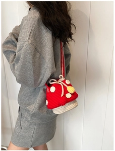Close-up of red and white crochet mushroom bag with drawstring on a child model