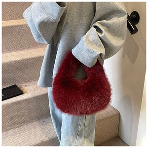 Détails d'un sac à main bordeaux en fausse fourrure douce avec une forme ronde chic