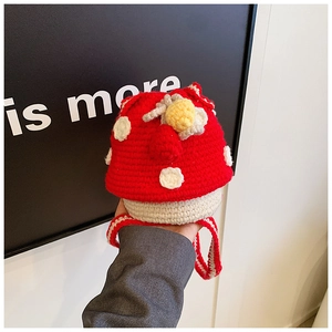 Detail of hand-knitted red mushroom drawstring bag with white polka dots and yellow flower