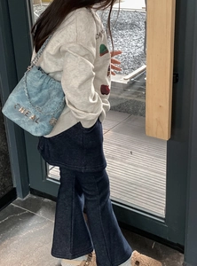 Detailansicht der hellblauen gesteppten Kettenschultertasche mit Metallbuchstaben am Modell