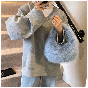 Détail d'un sac à main en fausse fourrure bleu clair avec une tenue d'hiver décontractée