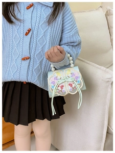 Close-up of floral embroidery and pearl handle on a green traditional Chinese kids handbag