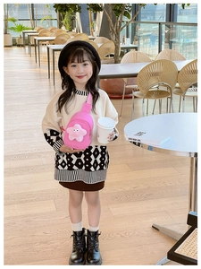 Borsa a tracolla rosa per bambini con ciondolo a stella in peluche indossata in un cafe