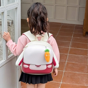 Sac à dos lapin mignon pour enfant, blanc crème et rouge avec charm carotte, porté par un enfant