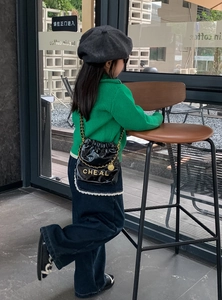 Detailansicht einer schwarzen gesteppten Kettenbeuteltasche für Kinder mit Herbstoutfit