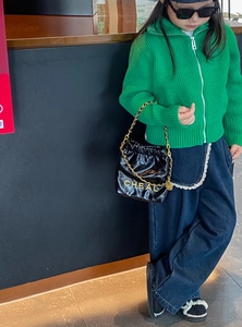 Detail eines Kindes in grünem Cardigan und Jeans mit Spitzenverzierung an der Tasche