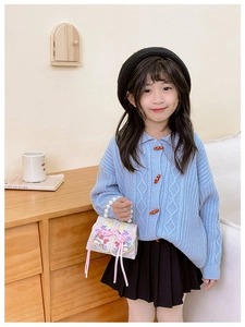 Close-up of girl's embroidered white handbag with pearl handle and bow detail