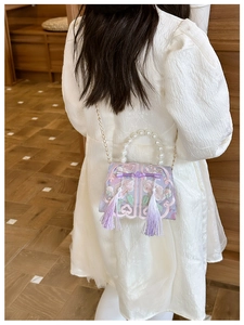 Detail of embroidered floral crossbody bag with pearl handle and tassels on model