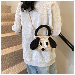 Detail of hand-crocheted beige puppy bag with long black ears and shoulder strap for kids