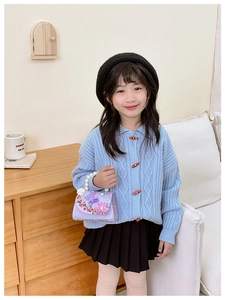 Detailed view of lavender handbag with pearl handle and floral accents on blue cardigan