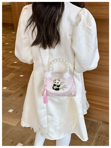 Pink crossbody bag with embroidered panda, pearl handle and tassels on a child dress