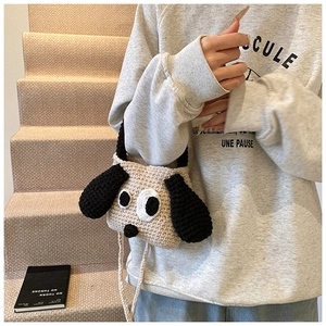 Detail of a handmade crochet dog shoulder bag with cute black ears on a beige background