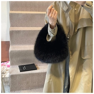 Détail d'un sac à main noir en fausse fourrure montrant la texture douce sur un mannequin