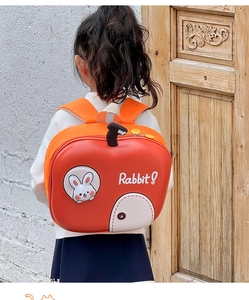 Dettaglio dello zaino per bambini arancione a forma di mela con toppa a forma di coniglio