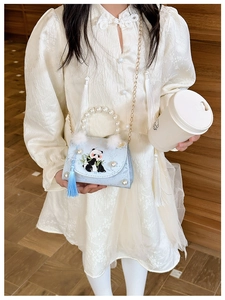 Close-up of panda embroidery and pearl handle detail on a blue children's shoulder bag