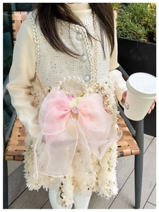 Close-up of pink organza bow with rhinestone and pearl handle on kids handbag