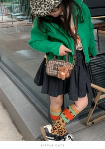 Close-up of stylish brown plaid mini bowling bag with a cute bear charm on a kid's outfit