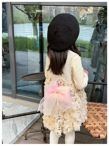 Detail of pink organza bow and white pearl handle on the fuzzy cream children crossbody bag
