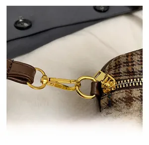 Detailed macro view of golden metal swivel hooks and zipper on a plaid bowling bag