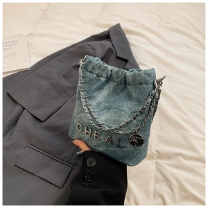 Detail der gesteppten Jeans-Beuteltasche mit Kettenriemen und Kamelien-Anhänger