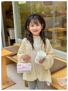 Tenue enfant avec cardigan tricoté, sac à perles rose et béret noir dans un décor de café